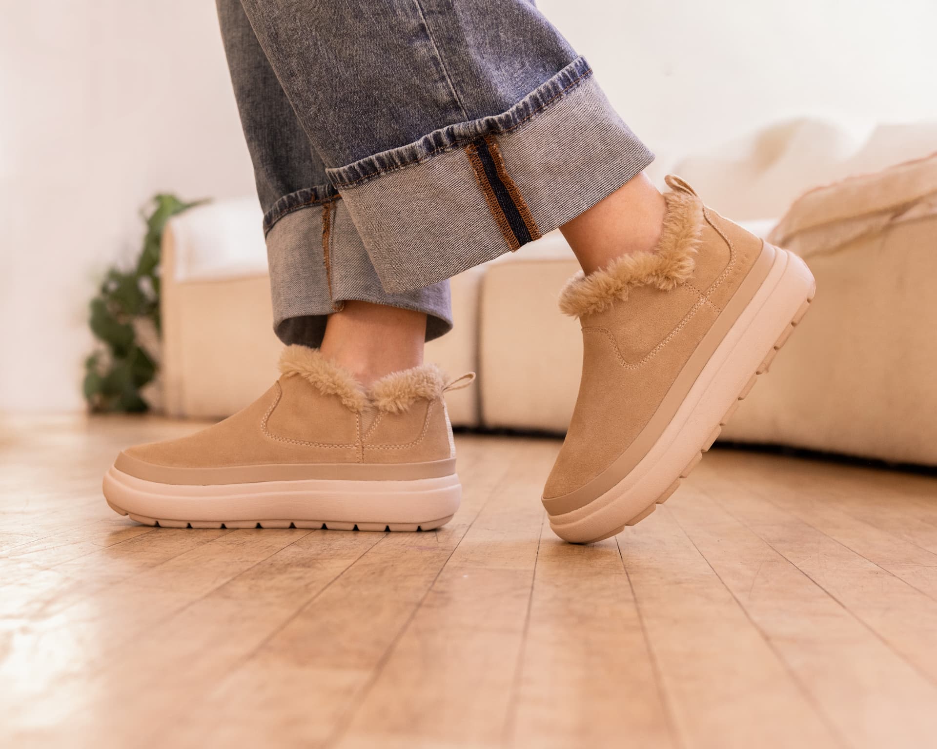 Woman wearing REEF Weekend warm sand suede shearling-lined boots on a wood floor